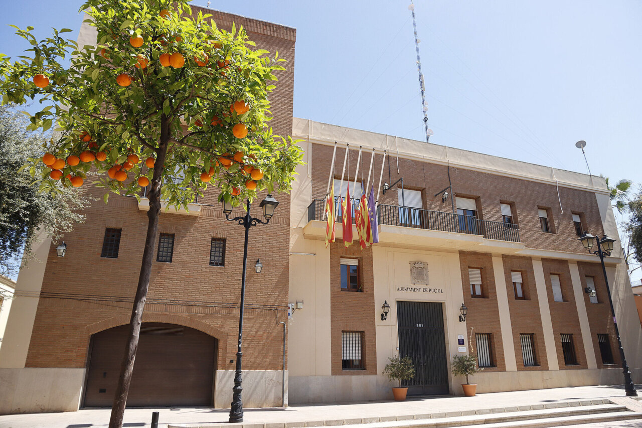Fachada del Ayuntamiento de Puçol con naranjos y banderas