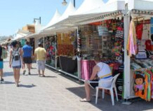 Casetas de venta en el paseo marítimo del Cabanyal con personas caminando.