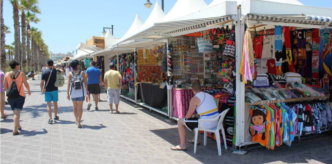 Casetas de venta en el paseo marítimo del Cabanyal con personas caminando.