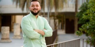 Enric Valls sonríe en un entorno urbano con palmeras.