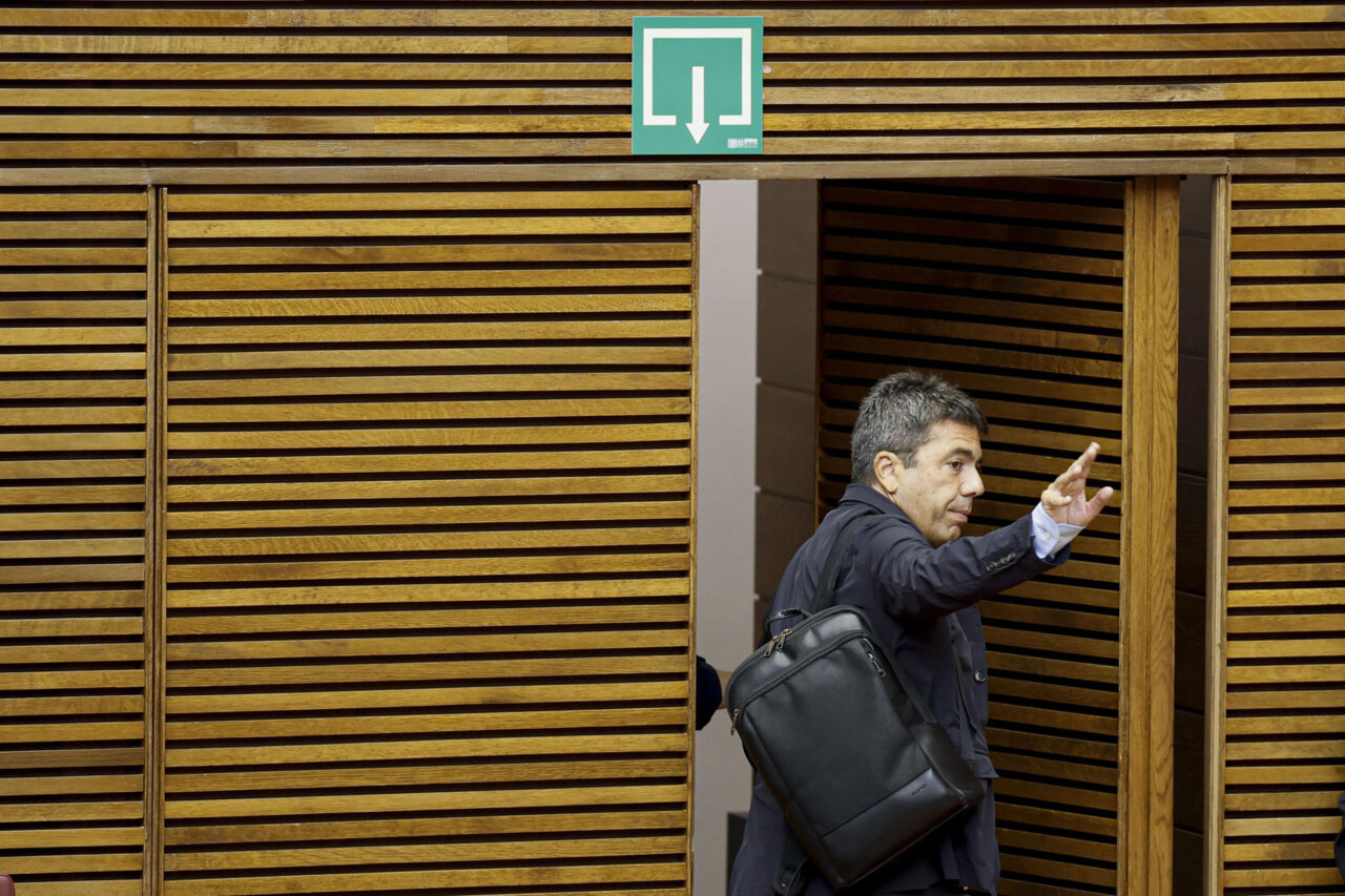 Carlos Mazón saliendo de un edificio con un gesto de despedida