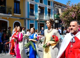 Rostros descubiertos y flores por cirios celebran la victoria de la vida con el Desfile de Resurrección en el Marítimo Grupo de personas en un desfile folclórico con trajes tradicionales