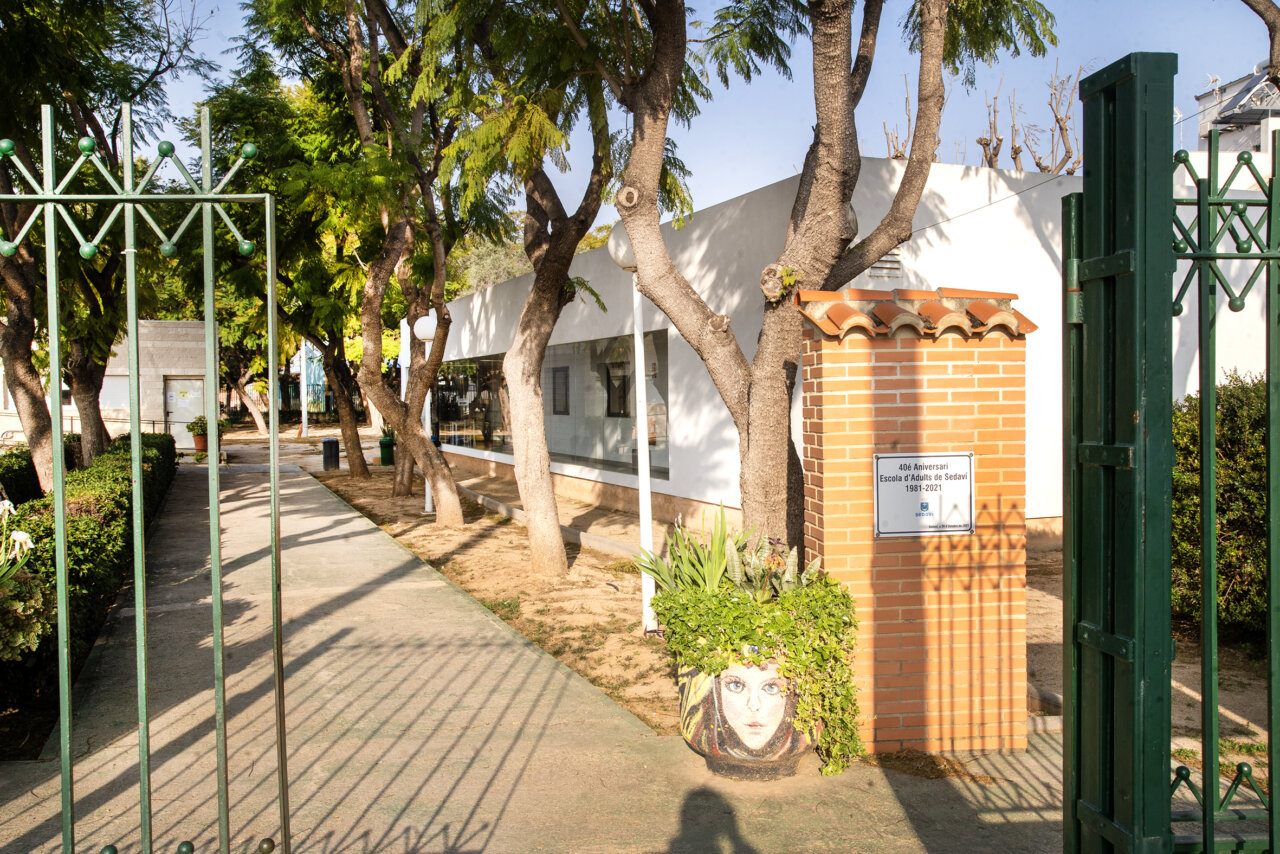 Entrada de la Escuela Pública de Adultos de Sedaví con árboles y un camino