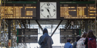 Pantalla de información en estación de tren con horarios y retrasos