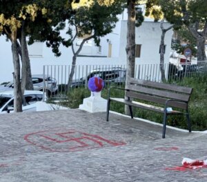 Grafiti de símbolo en el suelo junto a un banco en un parque.