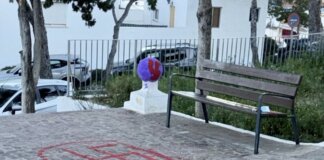 Grafiti de símbolo en el suelo junto a un banco en un parque.