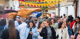 Multitud de personas en la feria asociativa de Benetússer con decoraciones coloridas