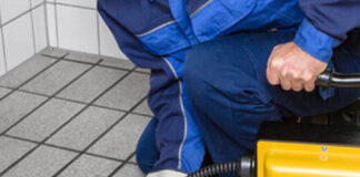 Hombre usando un desatascador de tuberías manual en el baño