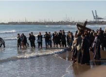 Ceremonia en la playa con imágenes religiosas y fieles rindiendo homenaje