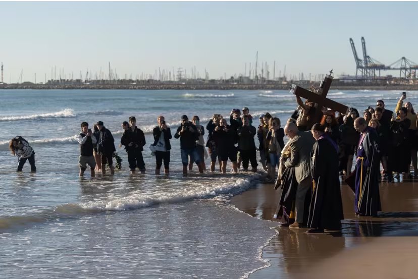 Ceremonia en la playa con imágenes religiosas y fieles rindiendo homenaje
