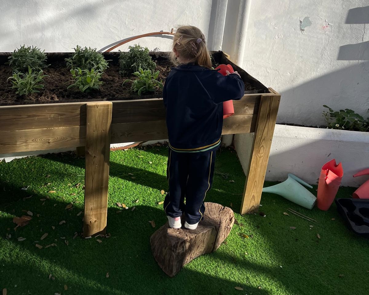 Niña regando plantas en el huerto escolar del colegio María Inmaculada