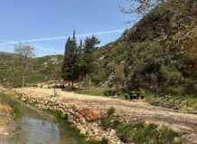 Zona natural restaurada con mesas y un arroyo en el entorno
