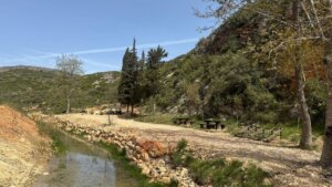 Zona natural restaurada con mesas y un arroyo en el entorno