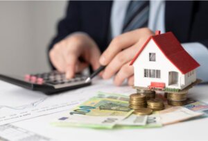 Persona calculando inversiones inmobiliarias con casa y dinero