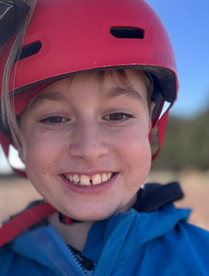 Niño sonriente con casco rojo y chaqueta azul