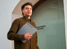 Joven sosteniendo una carpeta frente a la oficina de Labora en Valencia.