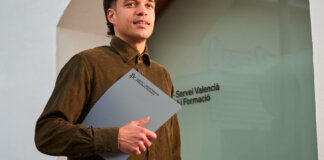 Joven sosteniendo una carpeta frente a la oficina de Labora en Valencia.