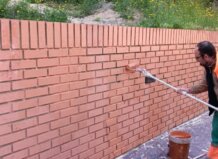 Operario limpiando grafitis en una pared de ladrillos en Paterna