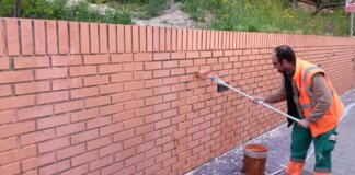 Operario limpiando grafitis en una pared de ladrillos en Paterna