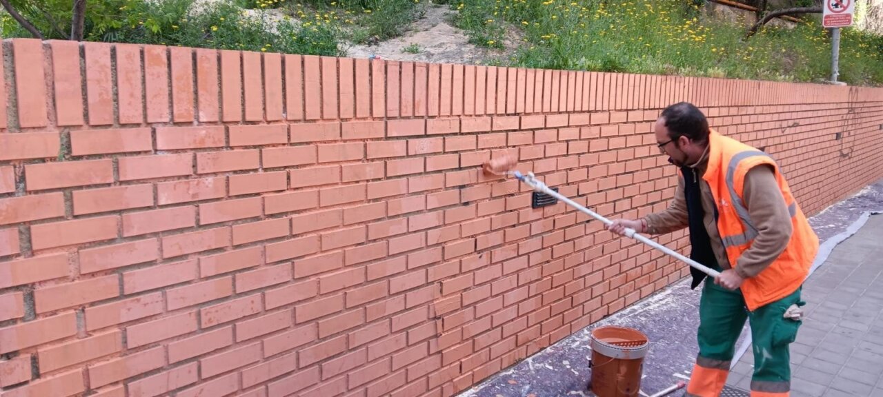 Operario limpiando grafitis en una pared de ladrillos en Paterna