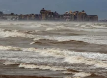 Vista de la niebla de advección sobre el mar y edificios costeros.