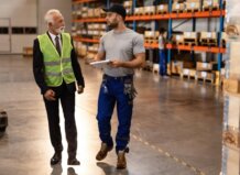Dos operarios conversando en un almacén con estanterías de productos