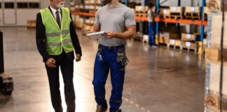 Dos operarios conversando en un almacén con estanterías de productos