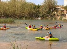 Jóvenes realizando actividades acuáticas en kayaks en un río