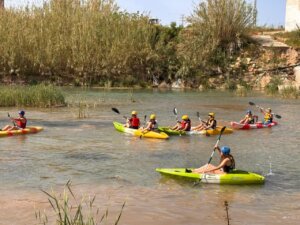 Jóvenes realizando actividades acuáticas en kayaks en un río