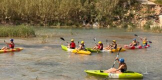 Jóvenes realizando actividades acuáticas en kayaks en un río