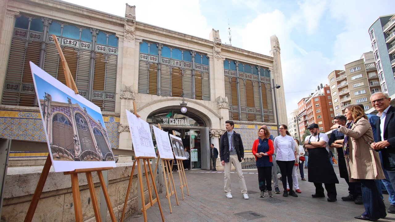 Grupo de personas frente al Mercat Central con planos del proyecto de limpieza.