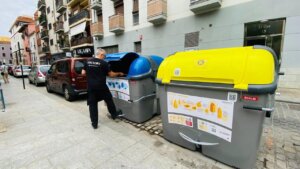 Persona depositando residuos en contenedores de reciclaje en la calle