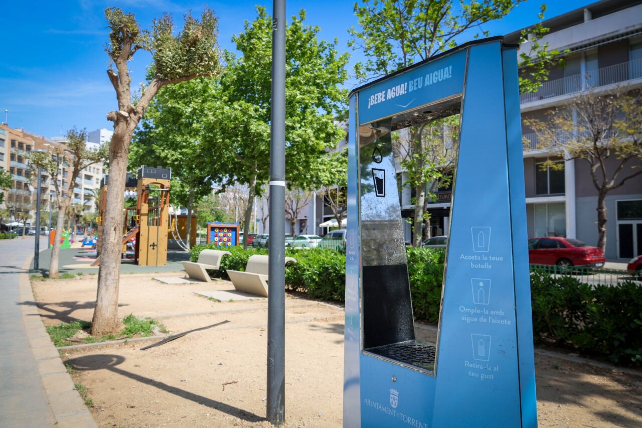 Fuente de agua potable en un parque de Torrent con árboles y juegos infantiles
