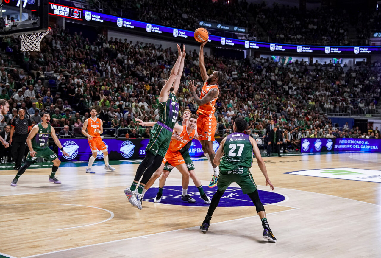Jugadores de Valencia Basket en un emocionante partido contra Unicaja en Málaga.