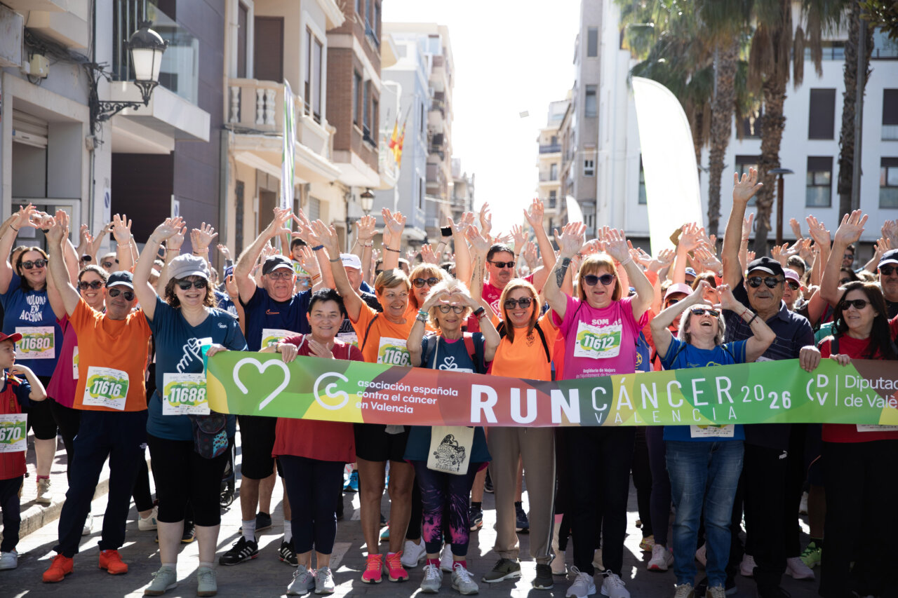 Participantes de la marcha solidaria RunCáncer en Benetússer levantando las manos