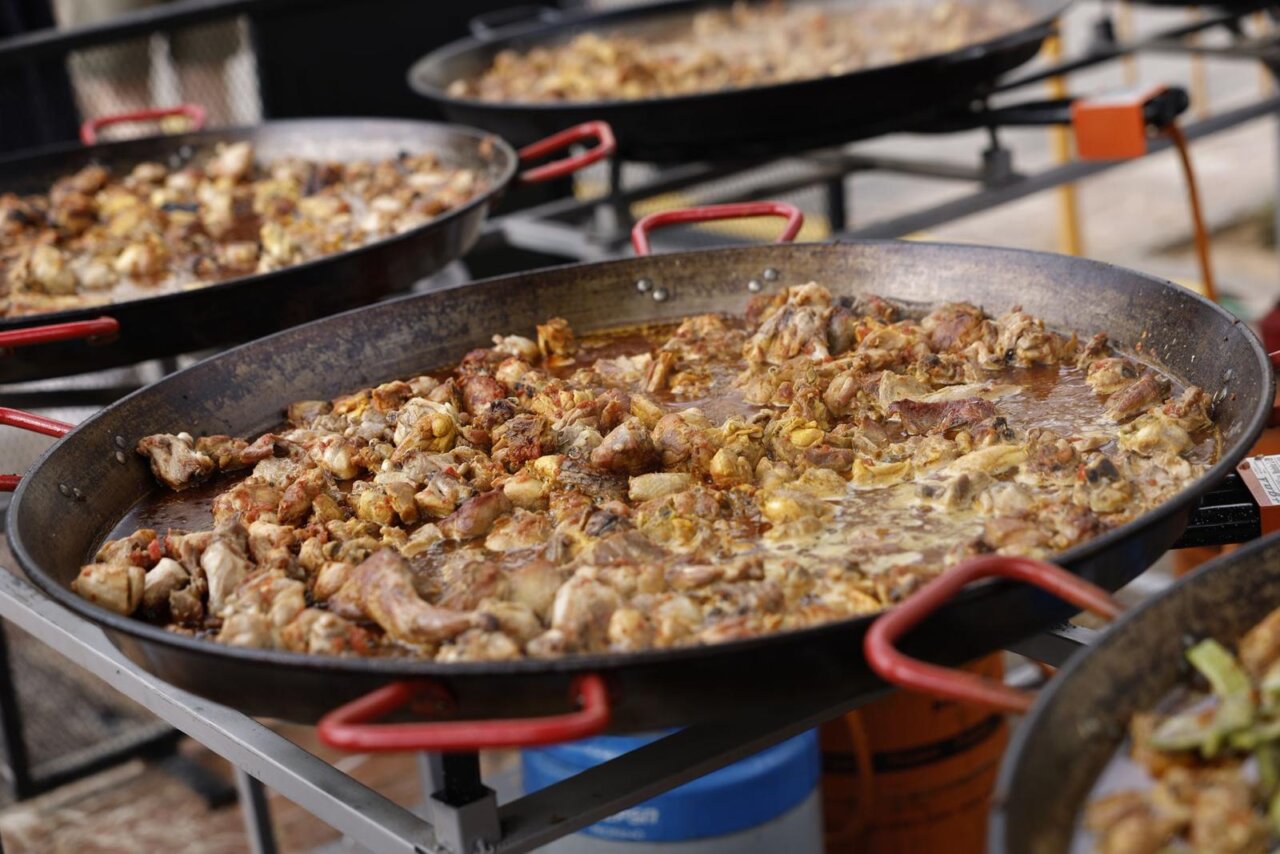Paellas cocinándose en el evento TastArròs en Valencia con carne y verduras.