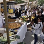 Gente disfrutando del TastArròs en València con paella y verduras frescas