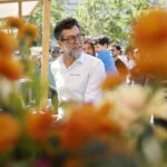 Hombre con gafas en un evento gastronómico rodeado de flores