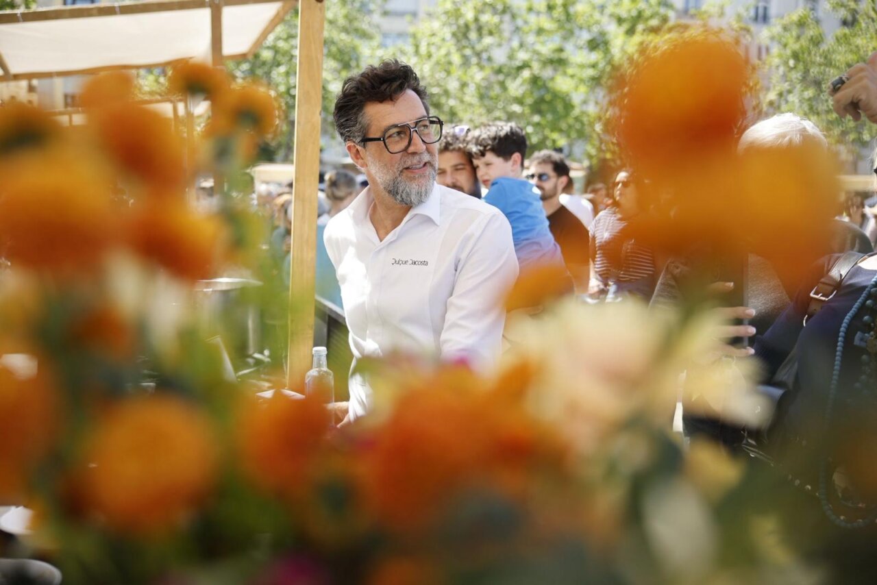 Hombre con gafas en un evento gastronómico rodeado de flores