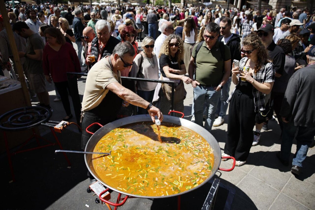 Chef preparando paella en el evento TastArròs en València con gran afluencia de público.