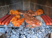Carne y salchichas asándose en una parrilla durante una torrà popular.