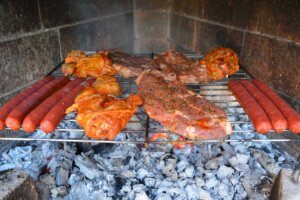 Carne y salchichas asándose en una parrilla durante una torrà popular.