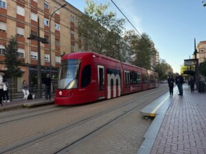 Tranvía de València circulando por la ciudad con pasajeros esperando en la parada.