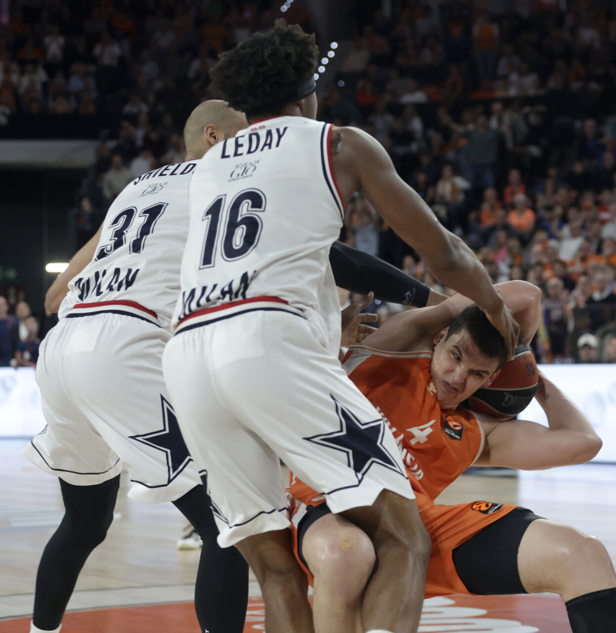 Jugadores de Valencia Basket y Olimpia de Milán en acción durante un partido de baloncesto.