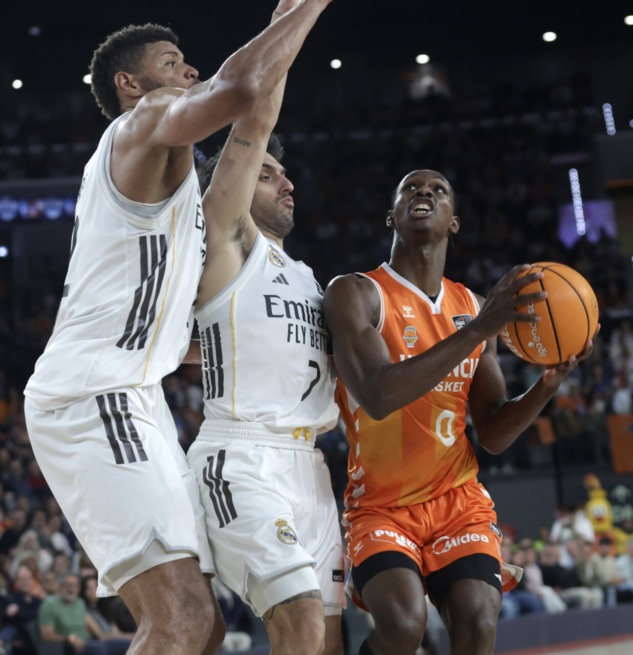 Jugadores del Valencia Basket y Real Madrid en acción durante un partido de baloncesto.