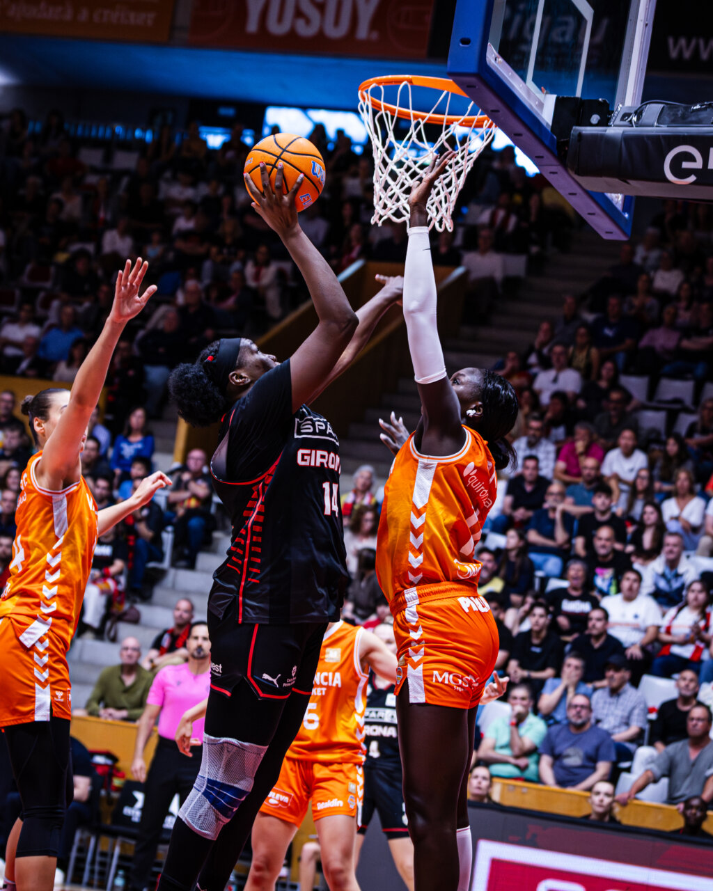 Jugadora de Spar Girona intenta encestar mientras es bloqueada por una jugadora de Valencia Basket.