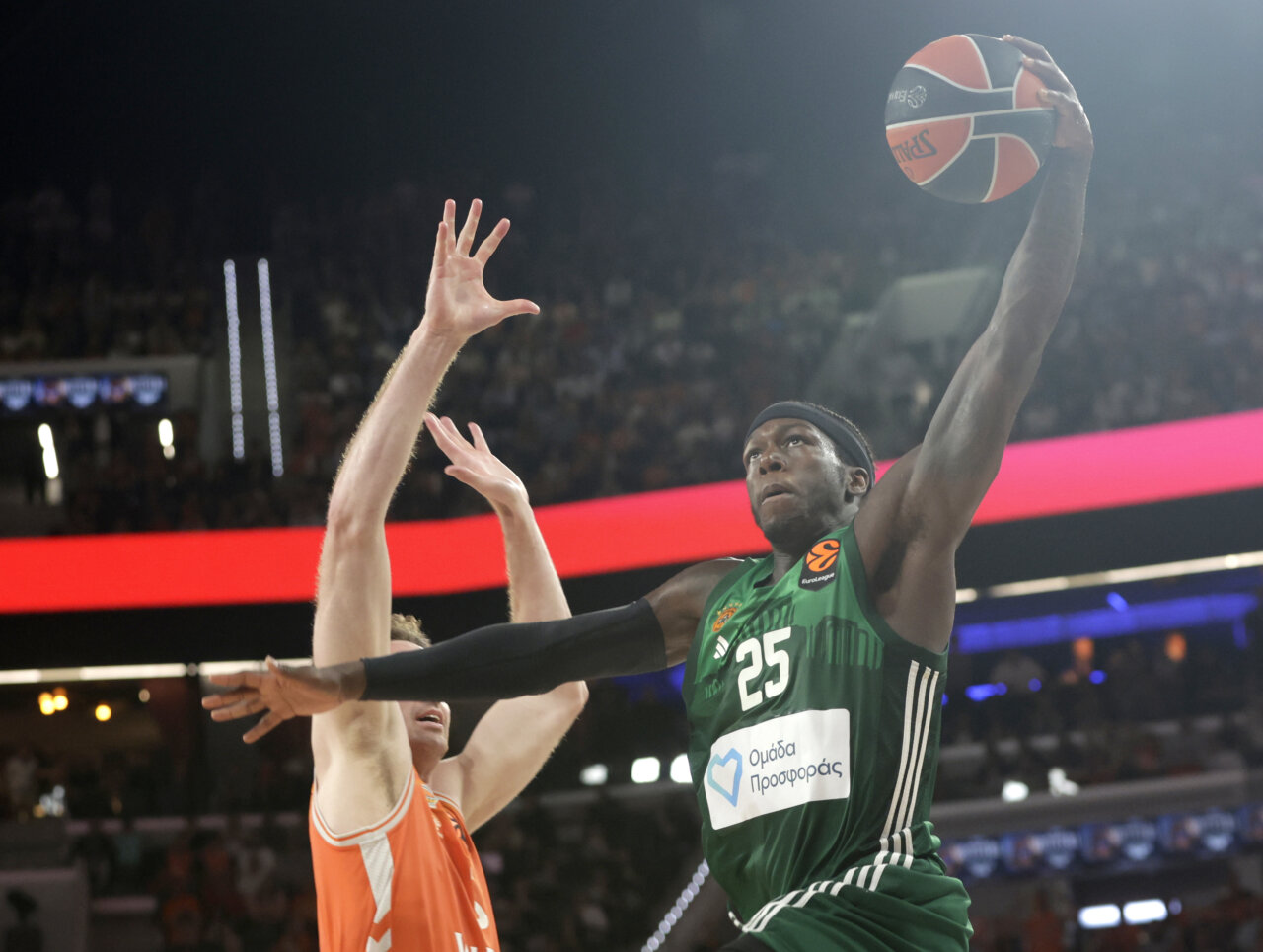 Jugador de baloncesto en acción durante un partido intenso entre Valencia Basket y Panathinaikos.