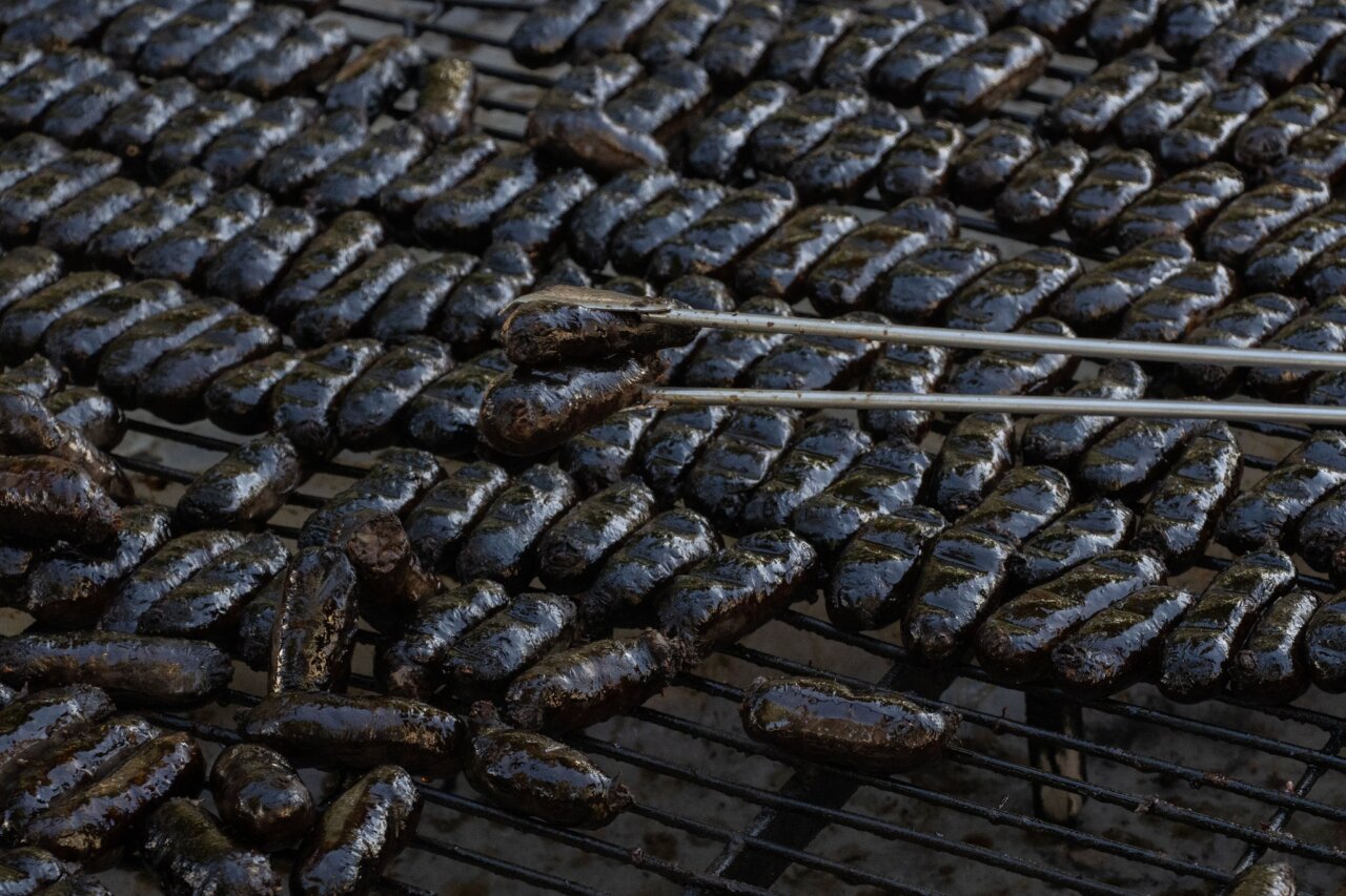 Parrilla con botifarras de Xirivella cocinándose al aire libre