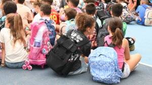 Grupo de escolares sentados en el suelo con mochilas coloridas