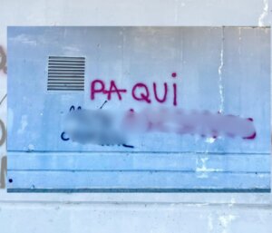 Pintadas en una pared con el nombre Paqui y otros insultos pixelados